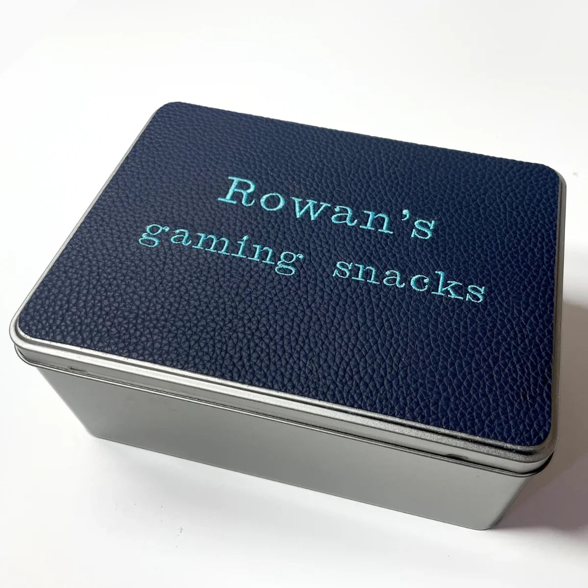 Personalized blue gaming snacks tin box with textured lid on white background