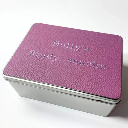 Metal tin box with textured purple lid labeled 'Holly’s Study snacks'.